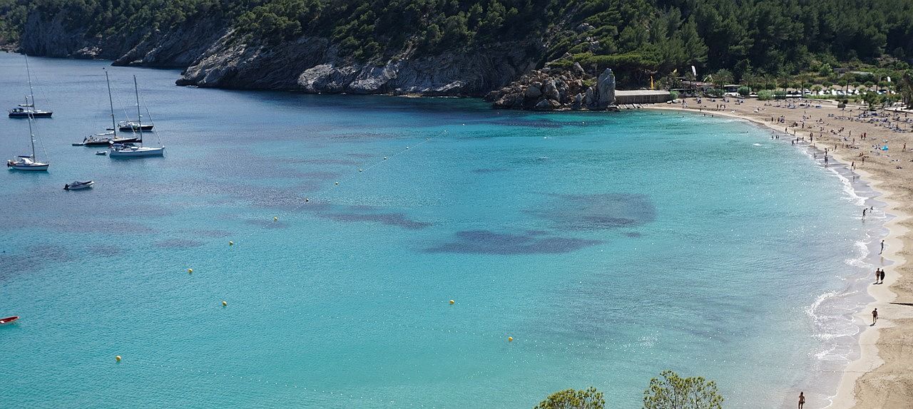 Un vol Ibiza pas cher avec Algofly illustré par une plage de sable jaune et une mer profonde.