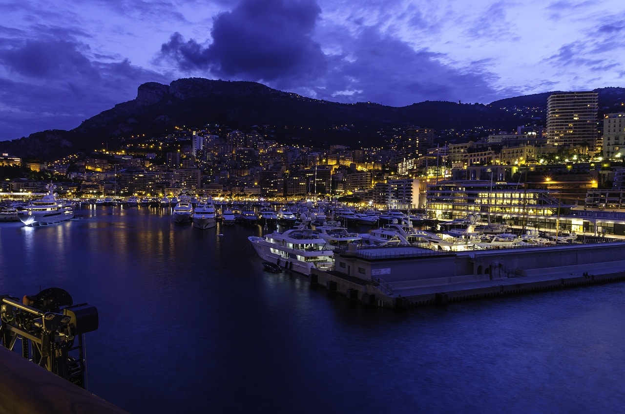 Un vol Monaco pas cher avec Algofly illustré par le port vu de nuit devant le rocher.
